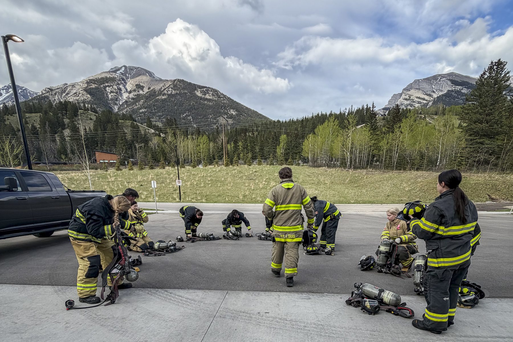 Firefighters working through self contained breathing apparatus drills on a training apron with the Alberta Rockies behind them.