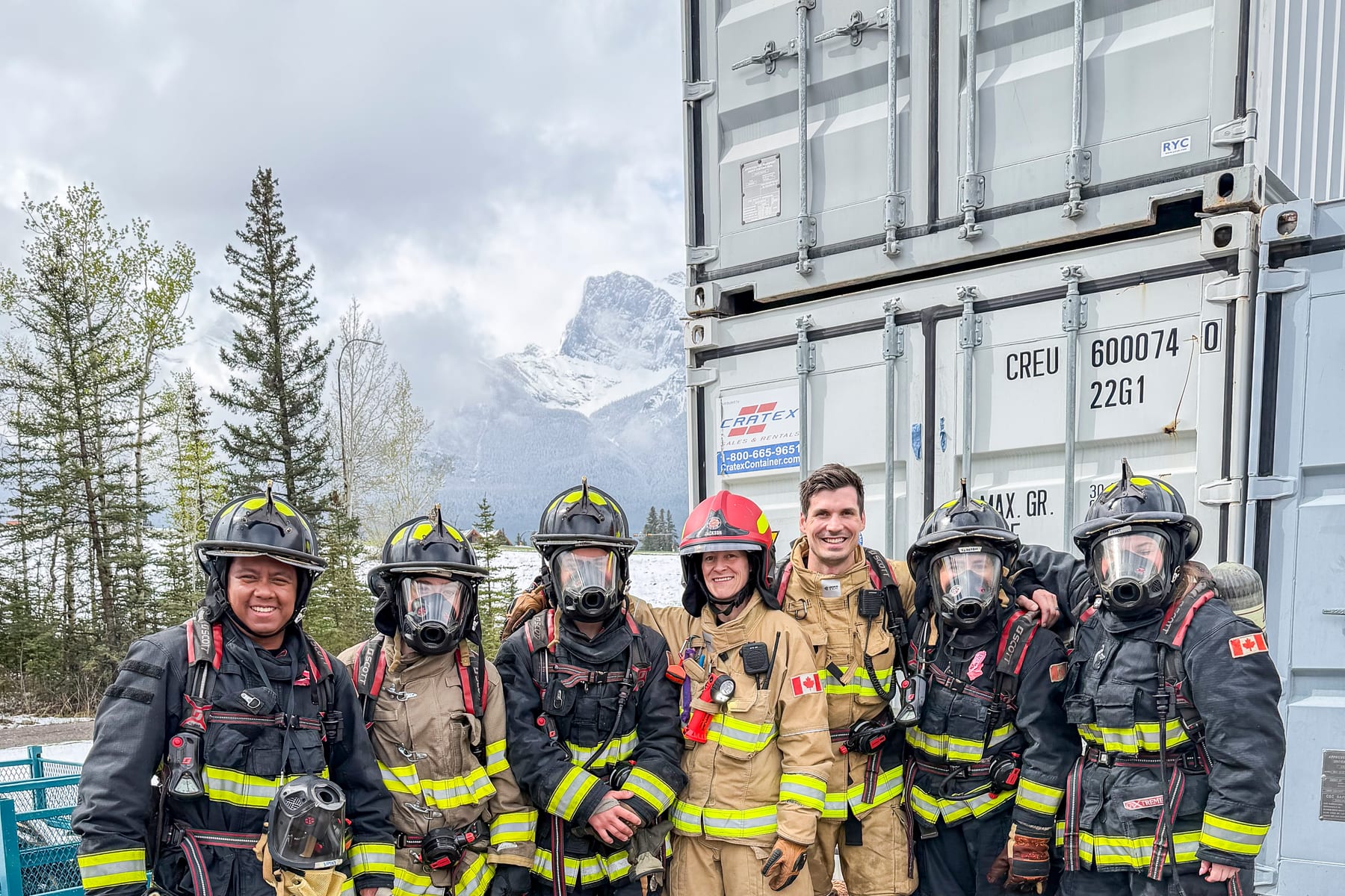 A crew of firefighters in full turnout gear standing together beside a charged hose line during a training evolution.